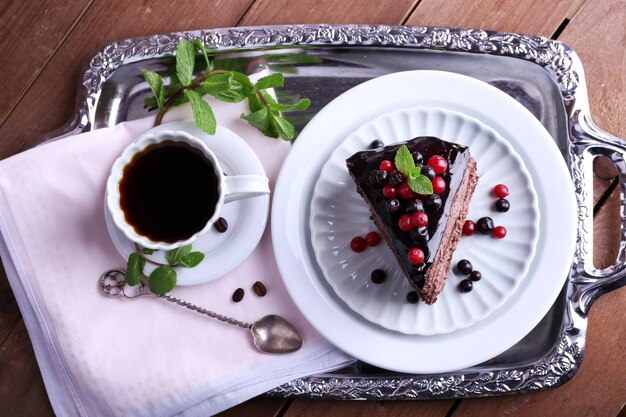 Délicieux gâteau au chocolat avec des baies et une tasse de café sur la table se bouchent