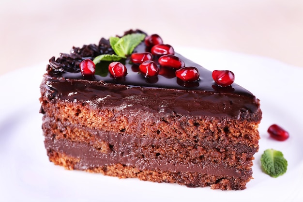 Délicieux gâteau au chocolat décoré de graines de grenade sur plaque sur table