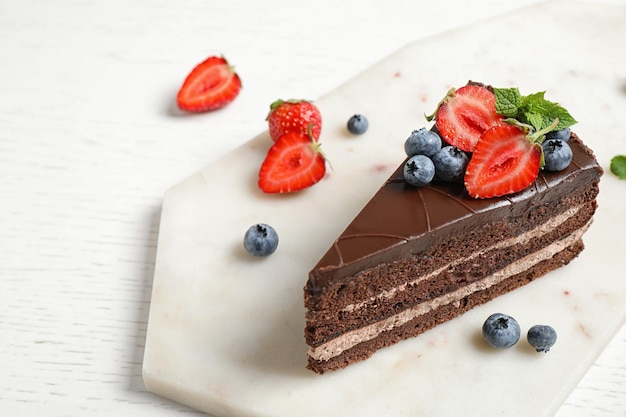 Délicieux gâteau au chocolat frais avec des baies sur tableau blanc