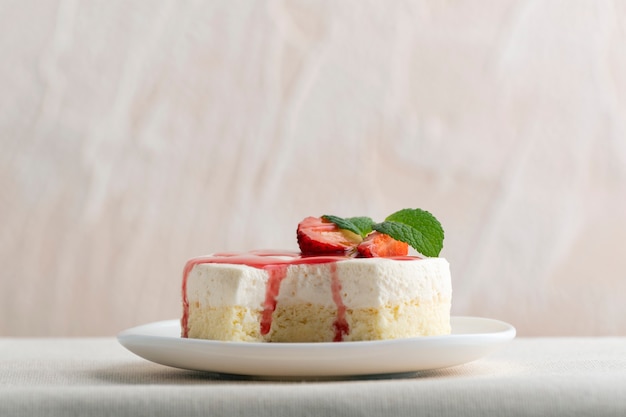 Délicieux gâteau au fromage avec des fraises fraîches et de la menthe sur une plaque blanche