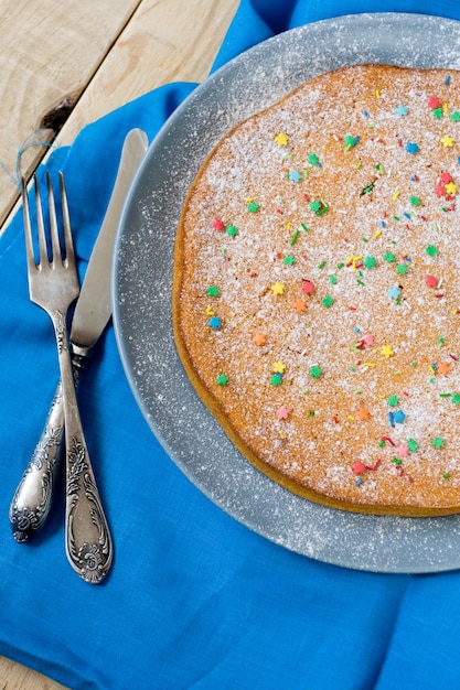 Un délicieux gâteau aux carottes sur une plaque allongée sur gris. Il se tient sur une table en bois non peinte.