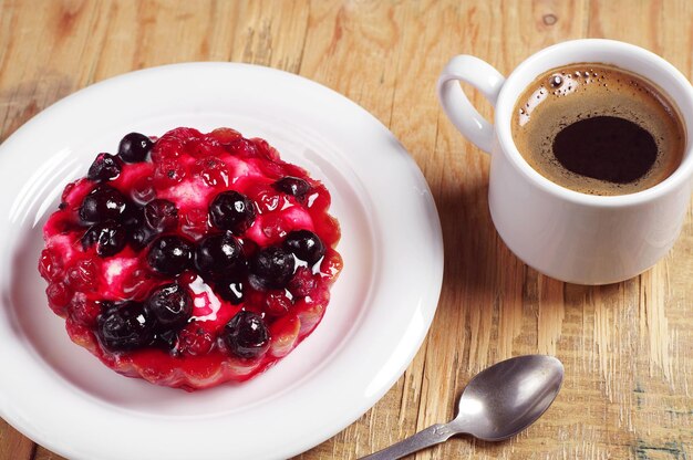 Délicieux gâteau aux groseilles dans une assiette et une tasse à café sur une vieille table en bois