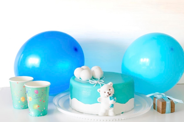 Délicieux gâteau bleu bébé décoré de gobelets en papier, d'une boîte-cadeau et de ballons pour le premier anniversaire de l'enfant. ensemble avec des décorations de couleurs bleues pour la fête de douche de bébé pour garçon