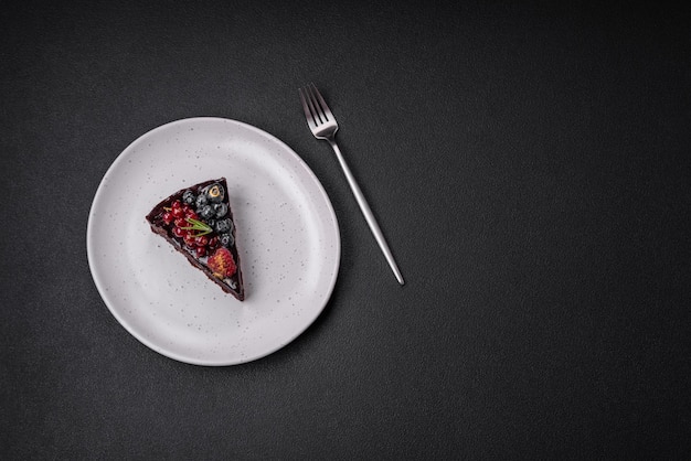 Délicieux gâteau brownie au chocolat sucré avec myrtilles, groseilles et framboises sur une plaque en céramique