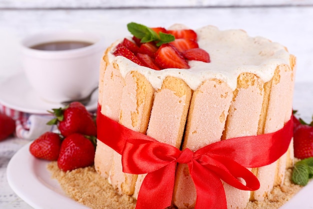 Un délicieux gâteau Charlotte avec des fraises fraîches sur une table en bois.