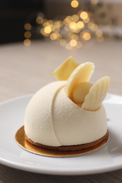 Délicieux gâteau mousse au chocolat blanc sur plaque contre gros plan lumières floues