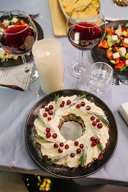 Délicieux gâteau de Noël sur une table à manger. Gros plan, grand angle. Il est décoré de baies et a un trou au milieu.