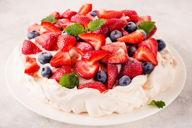 Délicieux gâteau Pavlova avec des fraises fraîches et des bleuets