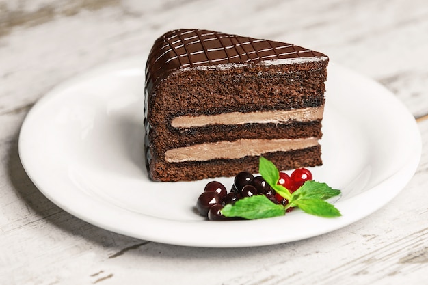 Délicieux gâteau sur une plaque blanche sur une table en bois