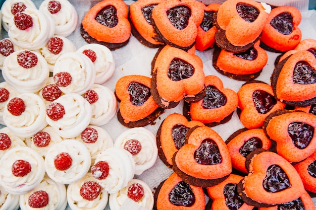 Délicieux gâteaux en forme de coeurs sur une table pour les invités Bonbons colorés pour une occasion spéciale sur un plateau Gros plan