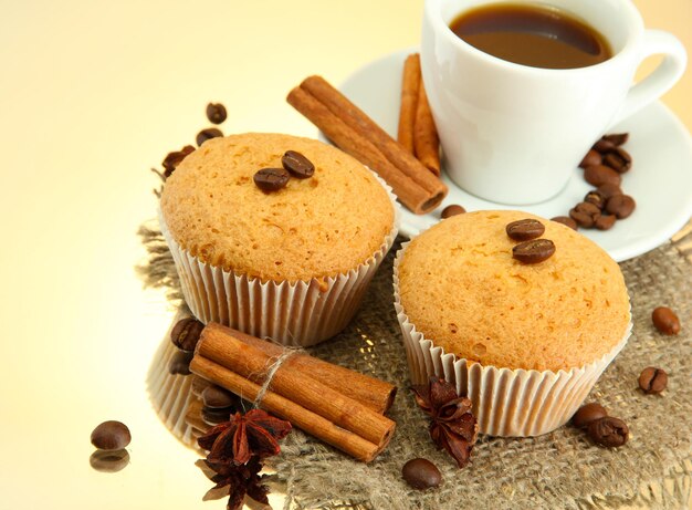 Délicieux gâteaux muffins aux épices sur toile de jute et tasse de café, sur fond beige