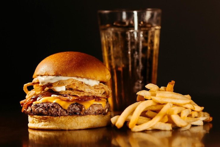 Photo un délicieux hamburger avec du bœuf, de la sauce tomate et des frites sur une table sombre.