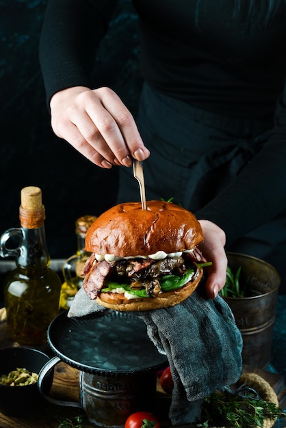 Délicieux hamburger grillé avec bacon et légumes Sur un fond sombre Concept de restauration rapide