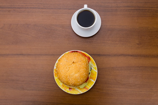 Délicieux hamburger et tasse de café sur table en bois. Vue de dessus