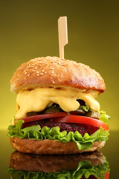 Un délicieux hamburger végétarien sur une surface de miroir sur un fond olive