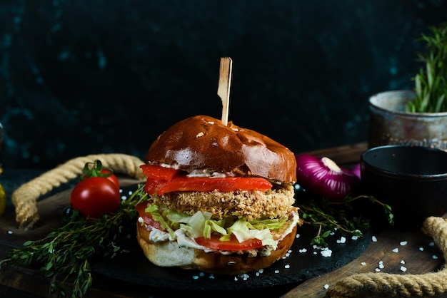 De délicieux hamburgers faits maison de fromage de boeuf et de légumes sur une vieille table en bois Concept de restauration rapide