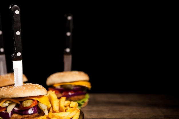 De délicieux hamburgers savoureux faits maison sur fond noir et bois. Nourriture rapide et savoureuse