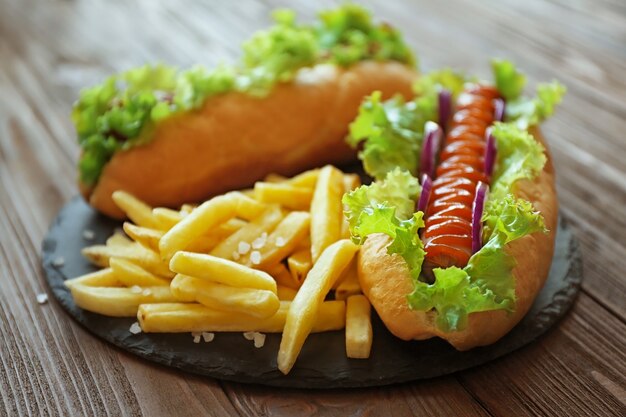 Délicieux hot-dog et frites sur planche de bois ronde