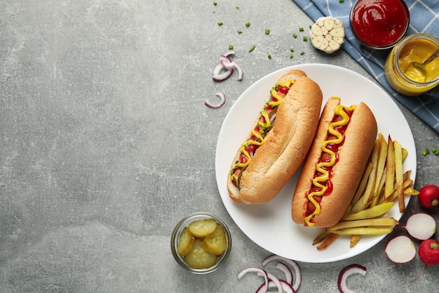 De délicieux hot-dogs et pommes de terre frites sur table grise, vue du dessus