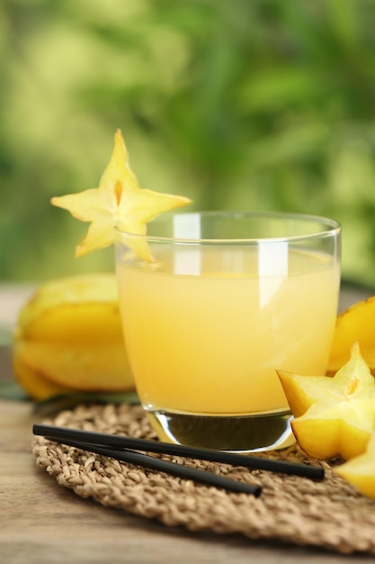 Délicieux jus de carambole et fruits frais sur une table en bois sur fond flou