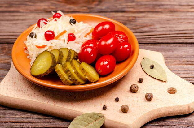 Délicieux légumes fermentés maison sur une assiette de choucroute, tomates marinées, cornichons, surface en bois