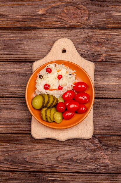 Délicieux légumes fermentés maison sur une assiette de choucroute, tomates marinées, cornichons, surface en bois