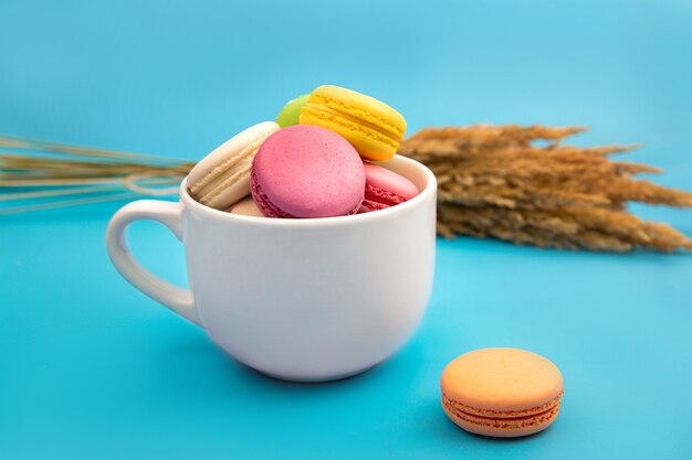 Délicieux macarons colorés sur fond bleu