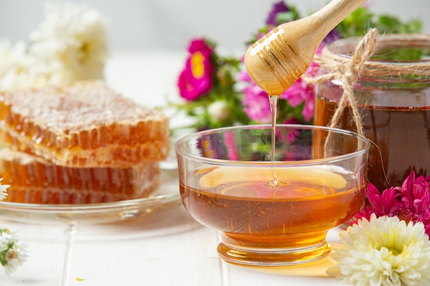 Délicieux miel avec louche de miel en bois sur une surface en bois blanche