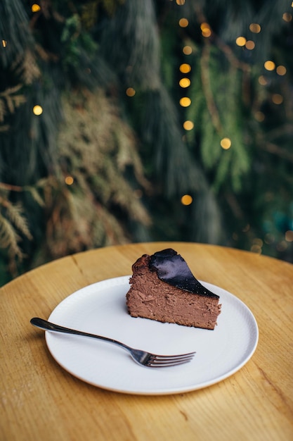 Un délicieux morceau de gâteau au fromage ou de tarte sur la table Fond de branches de pin et de guirlandes festives