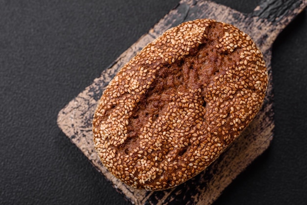 Un délicieux pain brun croustillant frais avec des graines et des céréales sur un fond de béton sombre
