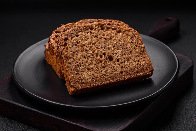 Délicieux pain brun frais et croustillant avec des céréales et des graines sur fond de béton foncé