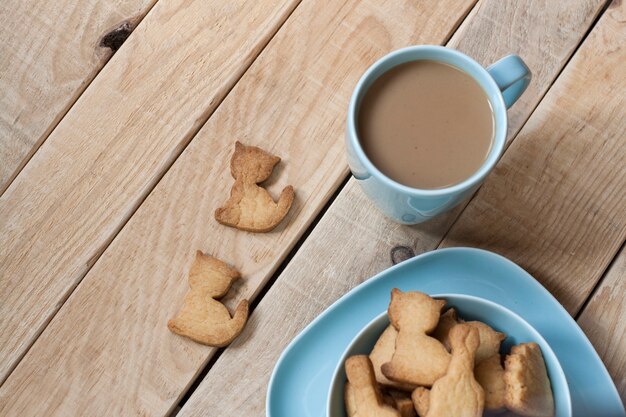 Délicieux Pain D'épices Cuit Sur Une Assiette Bleue, Une Tasse De Café De Lait à Une Table En Bois Clair.