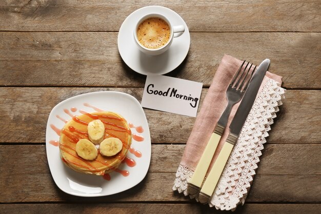 Délicieux petit-déjeuner et bonjour note de bienvenue sur table en bois, vue du dessus