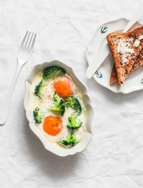 Délicieux petit déjeuner brunch œufs au four avec brocoli et mozzarella et pain grillé avec beurre sur un fond clair vue de haut