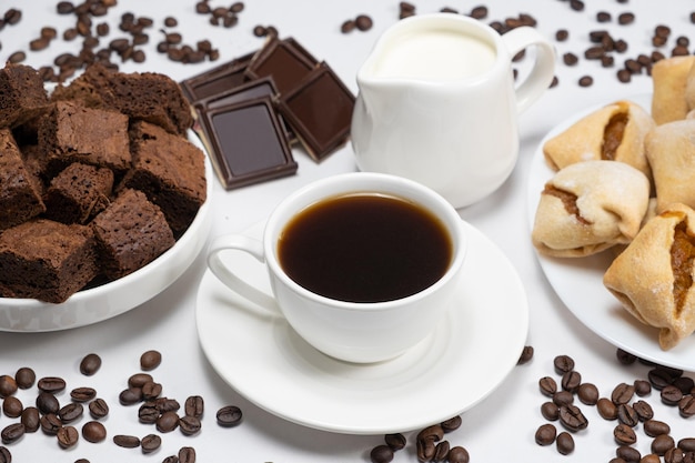 Délicieux petit-déjeuner café aromatique dans une tasse de chocolat au lait et des cubes de gâteau