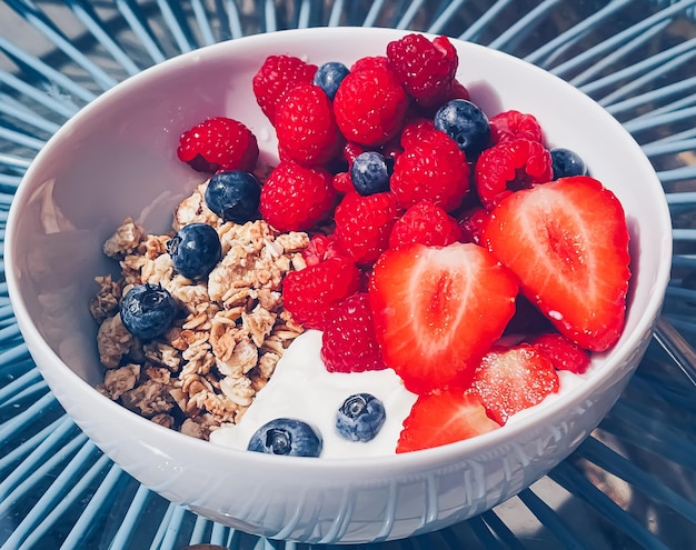 Délicieux petit-déjeuner avec céréales yaourt fraises framboises et myrtilles dans le jardin à l'extérieur alimentation saine et régime alimentaire