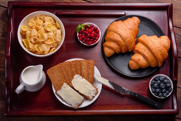 Délicieux petit déjeuner avec des croissants frais et des baies mûres sur une belle table en bois