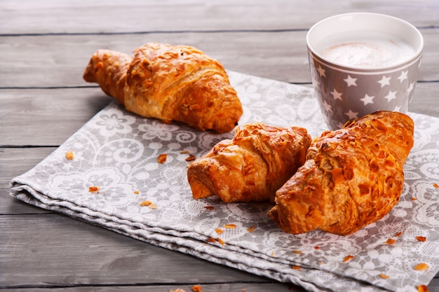 Délicieux petit déjeuner avec des croissants frais et tasse de cappuccino sur fond en bois gris