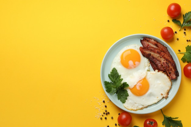 Délicieux petit déjeuner ou déjeuner avec des œufs au plat sur fond jaune, vue du dessus