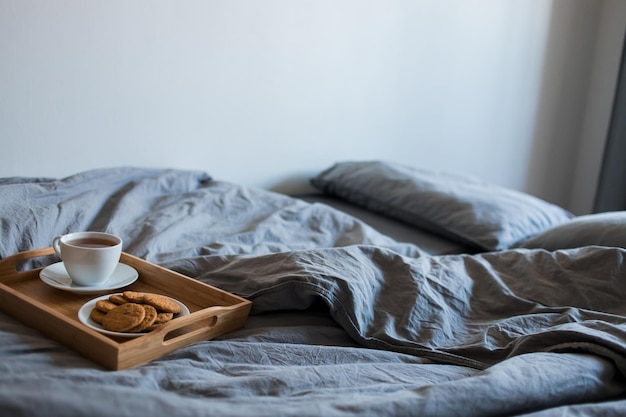 Un délicieux petit déjeuner est servi le matin. Une tasse de thé chaud et de biscuits au gingembre dans un plateau sur une couverture grise