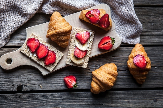 Un délicieux petit-déjeuner de fraises et de pain sur une table en bois. Fruits, nourriture, sandwichs, fromage. Style vintage. et