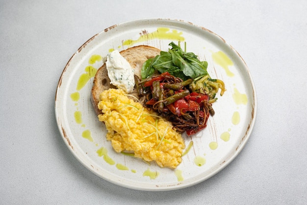 Un délicieux petit déjeuner avec des œufs brouillés, du fromage, des toasts et des légumes.