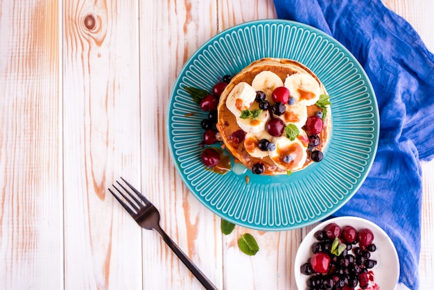 Délicieux petit-déjeuner sain et copieux sur le tableau blanc. Crêpes aux fruits, jus d'orange. Haut