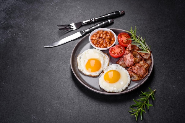 Un délicieux petit-déjeuner sain et nutritif avec des œufs au plat des haricots au bacon un verre de jus de biscuits à l'avoine du lait et de la confiture Une alimentation saine au début de la journée