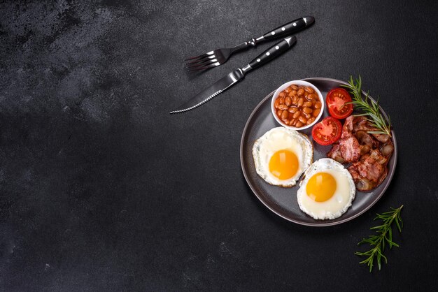 Un délicieux petit-déjeuner sain et nutritif avec des œufs au plat des haricots au bacon un verre de jus de biscuits à l'avoine du lait et de la confiture Une alimentation saine au début de la journée