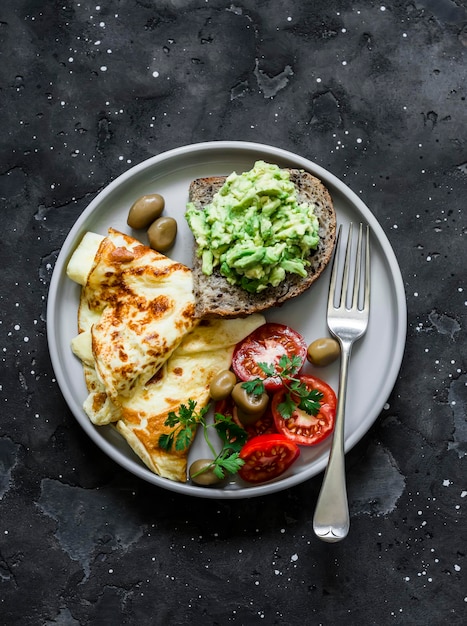 Délicieux petit-déjeuner sain omelette légumes toast à l'avocat sur fond sombre vue de dessus