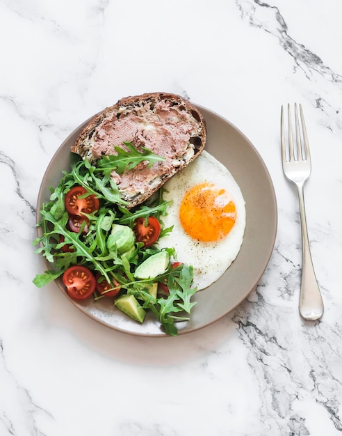 Délicieux petit-déjeuner sandwich au pâté de foie de poulet aux œufs frits et salade de légumes frais sur fond clair vue de dessus