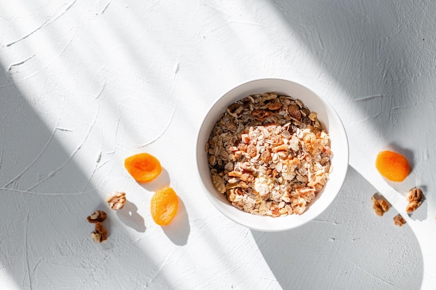 Délicieux petit-déjeuner végétalien cru sain avec de la farine d'avoine et des fruits secs sur un tableau blanc au lever du soleil avec des rayons de soleil, vue de dessus