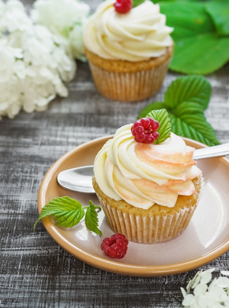 Photo délicieux petits gâteaux à la vanille avec de la crème et des framboises sur un bois foncé