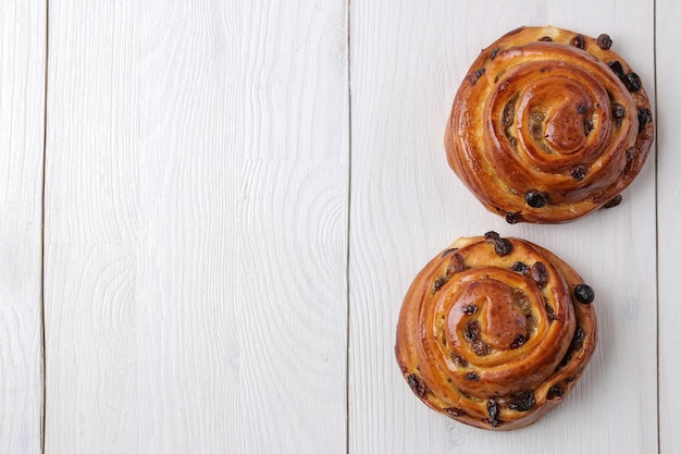 Délicieux petits pains aux raisins secs sur fond en bois blanc boulangerie fraîche petit-déjeuner vue de dessus avec un espace pour le texte